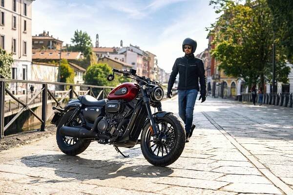A rider on a Keeway V302 C is walking toward his motorcycle