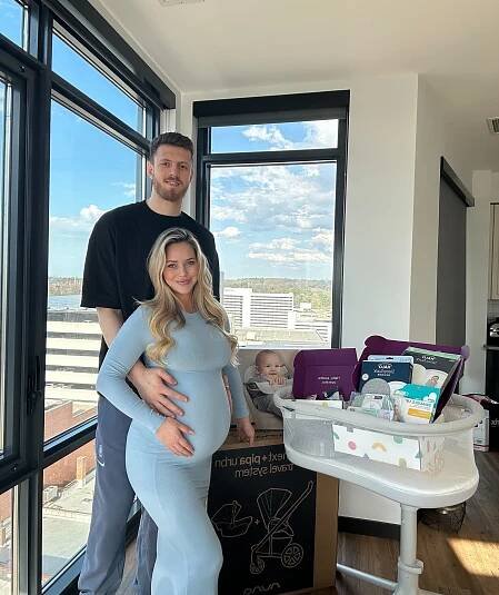 Pregnant woman and man with baby in bassinet and baby supplies.