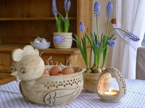 a table topped with vases filled with flowers and an egg sitting in a basket