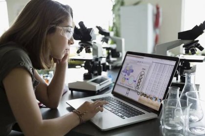 College student using laptop in science laboratory.