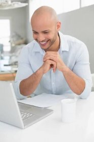 Portrét smějící se příležitostné mladého muže s notebookem sedět doma — Stock obrázek