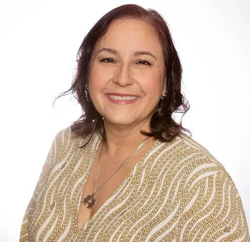 A woman wearing a striped shirt and a necklace smiles for the camera.
