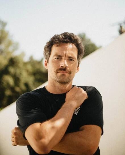 a man standing with his arms crossed and looking at the camera