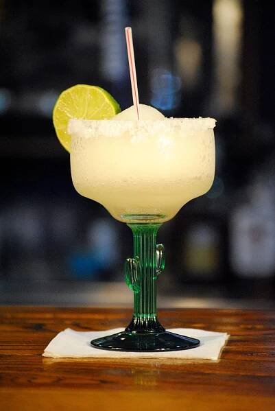 Margarita with a lime garnish in a fancy glass with a cactus stem from The Plaza Restaurant & Bar