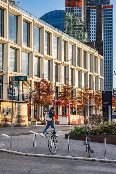 A new building near the Williamsburg waterfront. A pedestrian is seen near a street sign that reads “Grand St.”