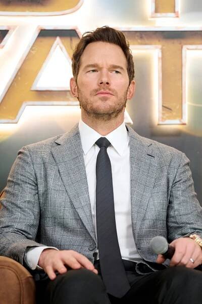 Chris Pratt seated, holding a microphone