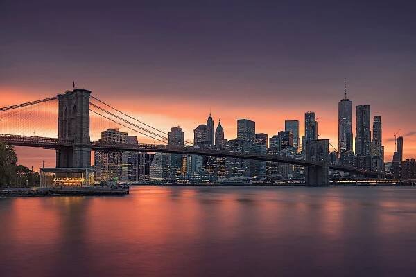 Slavný Brooklynský most v New Yorku s finanční čtvrtí - v pozadí v centru Manhattanu. Vyhlídková loď na East River a krásný západ slunce nad Janiným kolotočem. — Stock obrázek