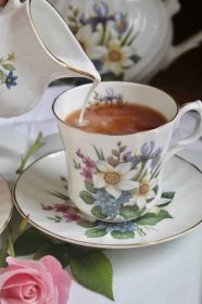 pouring milk into teacup to serve with afternoon tea scones