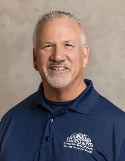 A man with a beard and a blue shirt is smiling for the camera.