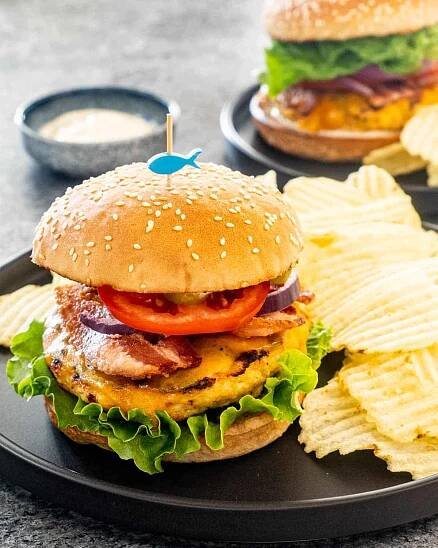 a chicken ranch burger on a plate with potato chips.