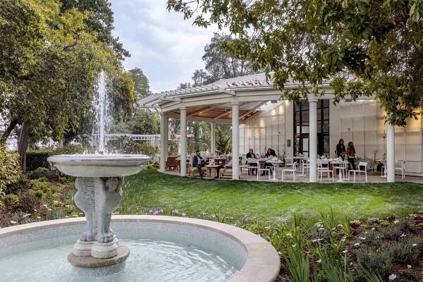 A large fountain near a grass lawn near dining patio.
