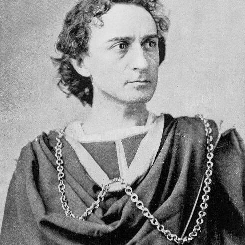 A person in historical attire with an ornate chain draped across their shoulder stares into the distance