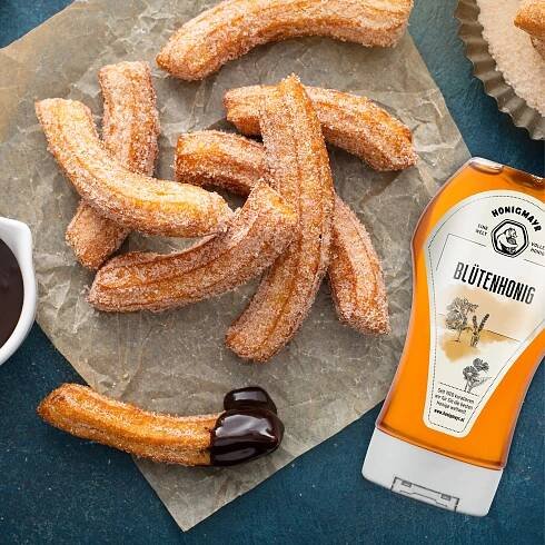 Churros mit einer Packung Blütenhonig daneben