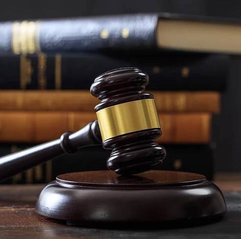 Judge gavel on a wooden desk, law books background