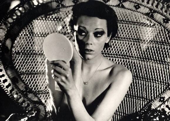 a woman without a shirt is looking at herself in a mirror