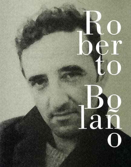 Grainy black and white photograph portrait of Roberto Bolaño, a man with deep set eyes and thick eyebrows, wearing a black jacket with a popped collar.