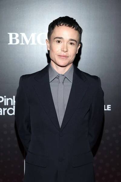 Elliot Page in a suit smiling at an event