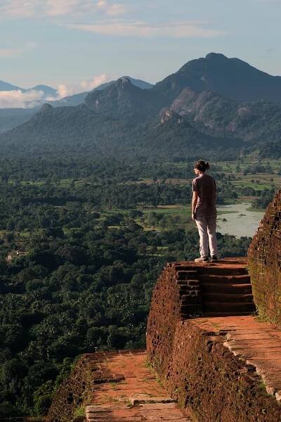 A person stood atop steps looking out at the vista from Sigiriya Rock, Sigiriya in the morning sunlight.