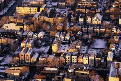 An aerial image of a city neighborhoods with cottages, low-rise apartments, and open lots. 