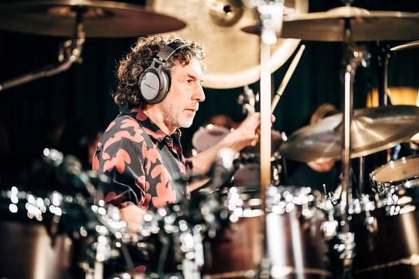 Drummer Simon Phillips playing the drums while wearing headphones