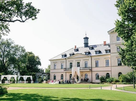 A luxurious wedding ceremony set in the elegant surroundings of Chateau Mcely, adorned with floral arrangements.