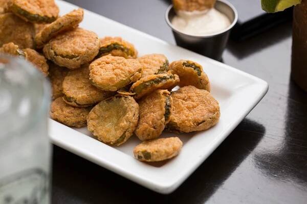 A plate piled high with golden-brown chicken nuggets, accompanied by a bottle and a small bowl of salt.