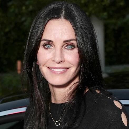 Courteney Cox with straight, glossy hair and shimmery burgundy, pink-ish eye makeup