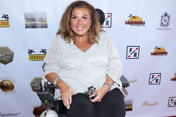 Abby Lee Miller sitting in a wheelchair while on a red carpet.