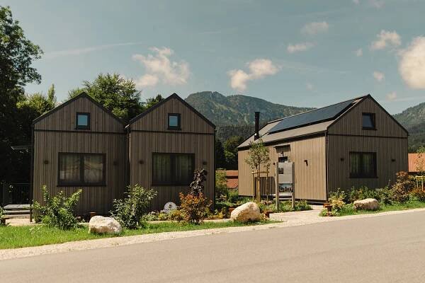 Drei moderne Tiny Häuser mit Holzverkleidung vor einer Bergkulisse, präsentiert für individuelles WOLF Haus Design.