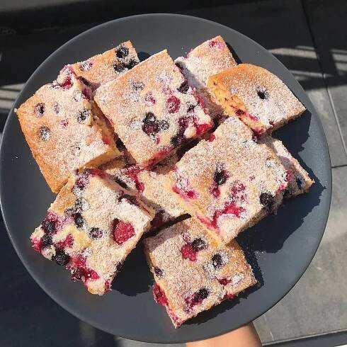 a black plate topped with blueberry bars covered in powdered sugar on top of a table