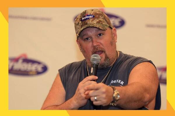 Larry The Cable Guy points at the crowd with a microphone in hand.