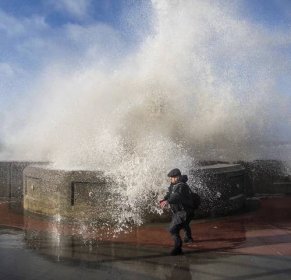 A passerby is caught off guard by a huge wave on Blackpool promenade this morning
