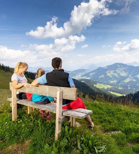 Familie Wandern auf Aussichtbank Schatzberg Blick isn Tal Wildschönau Rechte Wildschönauer Bergbahnen FG shoot