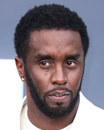Sean Combs stands in front of a blue backdrop.