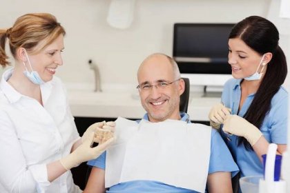Zubař zuby modelu vysvětlovat usmívající se samec pacientovi — Stock fotografie