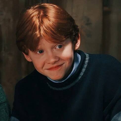 a young boy with red hair smiling at the camera