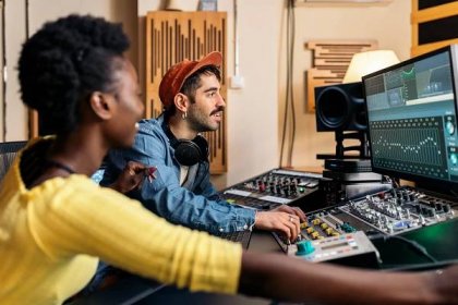 Stock fotografie šťastného černého zpěváka pracující v profesionálním hudebním studiu s mladým hudebním producentem. — Stock obrázek