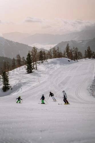 a group of four people skiing down a snow covered slope at ALPRIMA Aparthotel Hinterstoder in Hinterstoder