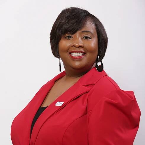 Michelle  is smiling against a gray background.