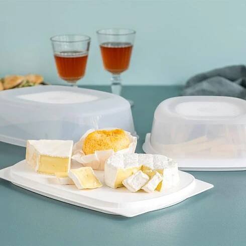 Různé druhy sýrů na tácku s dózou na sýry Tupperware CheeSmart v pozadí.