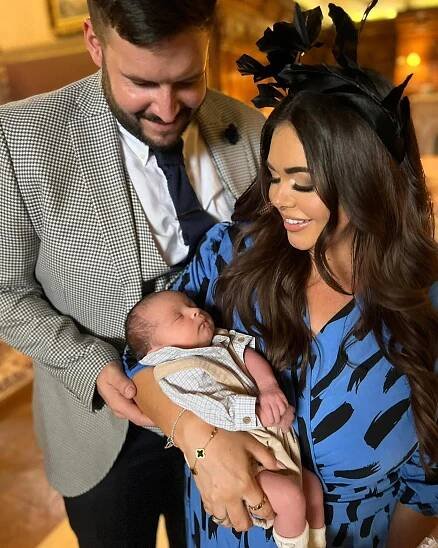 Scarlett Moffatt and her partner holding their baby at a wedding.