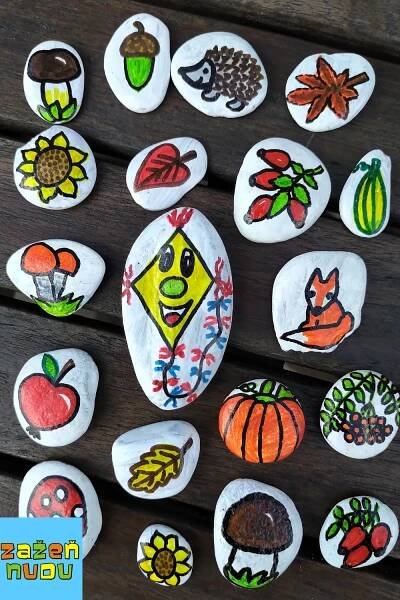 several painted rocks with different designs on them sitting on a wooden table next to leaves and acorns