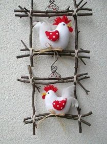 two white and red roosters are hanging on a wire wall ornament that is made out of twigs