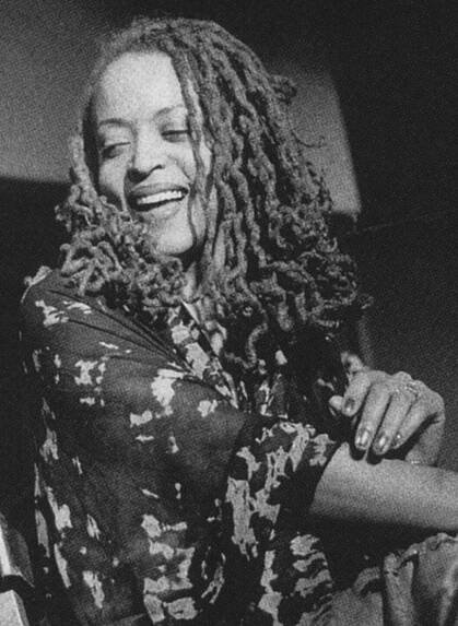 Black and white photograph of a smiling Cassandra Wilson looking to the side.