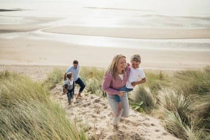 Pohled zezadu na rodiny se dvěma dětmi sejdete dolů ke břehu na dovolené. — Stock obrázek