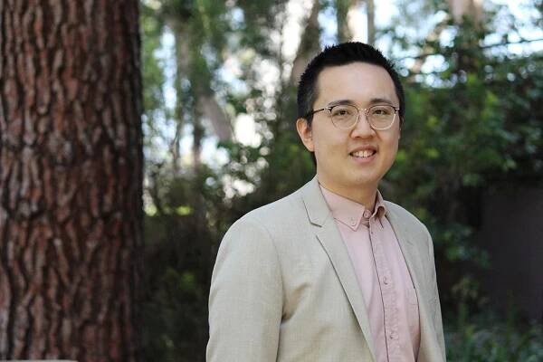 Eric Min outdoors in peach button-down and beige jacket