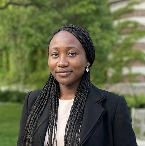 Northeast Maglev Intern Comfort Oshagbemi posing in a suit with trees in the background.