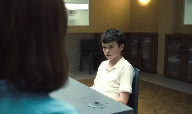 Boy sitting at a table, looking at a woman off-camera.