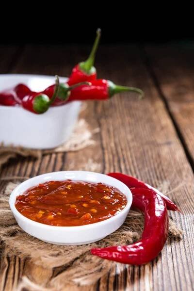 Sambal oelek in a bowl with whole red chiles on the side.