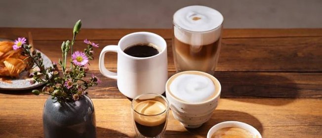 Verschiedene Kaffeemaschinen, Milchkännchen und Tassen auf einer Küchenablage